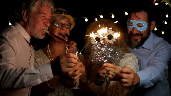 group of four people enjoying new year night celebrating with sparklers in the middle alt