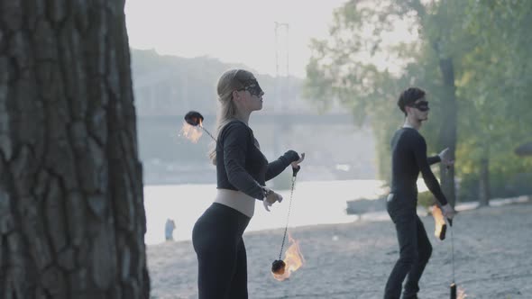 Young Beautiful Girl and Handsome Man in Black Clothes Performing Show with Flame Standing alt