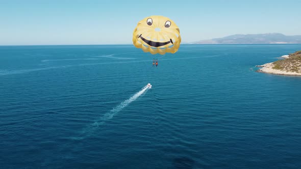 Drone flight next to parachutists engaged in parasailing. The parachute is tied to a motor boat. alt