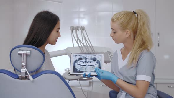 Dentist and Patient Choosing Treatment in a Consultation with Medical Equipment in the Background alt