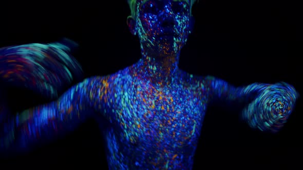 Man Covered with Phosphor Paint Dances Under Ultraviolet Light in Studio on Dark Background Front alt