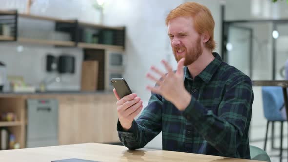 Unhappy Beard Redhead Man with Loss on Smartphone in Cafe  alt