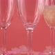 Pouring sparkling wine into glasses on a pink background with heart-shaped confetti. - VideoHive Item for Sale