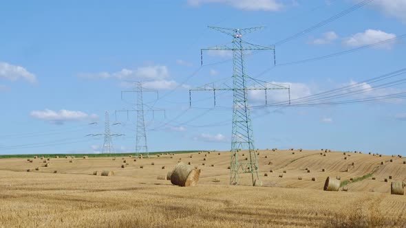 Straw bales on the field near high electricity pylons