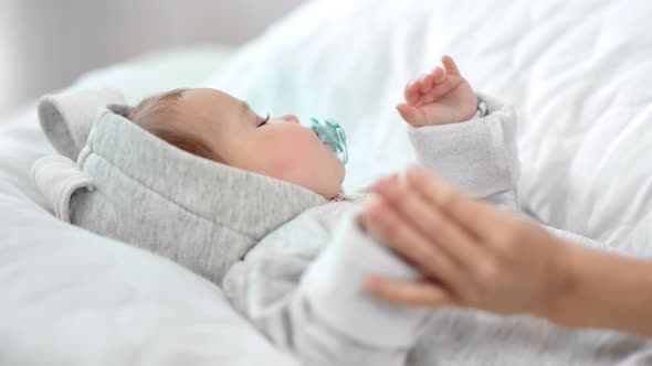 Carefree Little Baby with Nipple Sleeping on White Bed During Mother Hand Caress His Arm Closeup alt