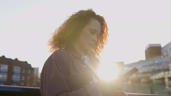 Young woman using smartphone in the city at sunset