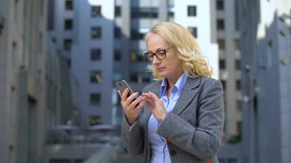 Aged Lady Boss Showing Success Gesture Using Smartphone Application, Messenger alt
