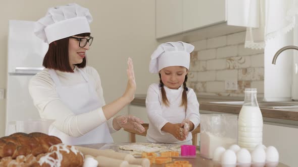 Caucasian Mother and Adorable Daughter in Hats of Chef and White Apron Enjoying Cooking Together alt