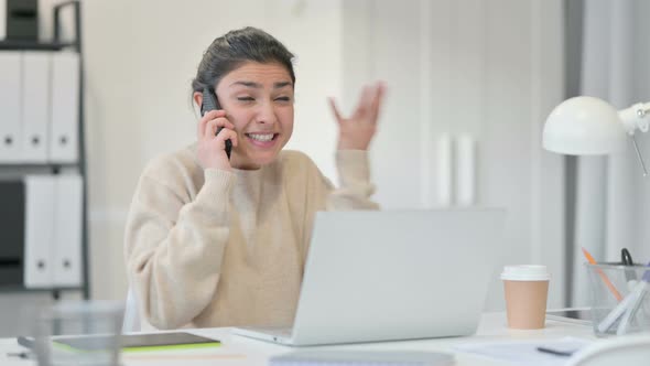 Indian Woman with Laptop Angry on Smartphone  alt