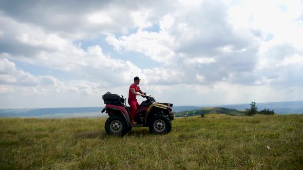 Man in a Black Cap and Red T-shirt on a Colored ATV Rides alt