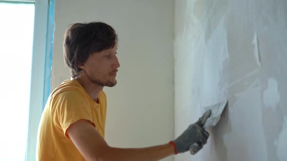 A Young Man in a Yellow Tshirt is Doing a Walls Renovation in His Home alt