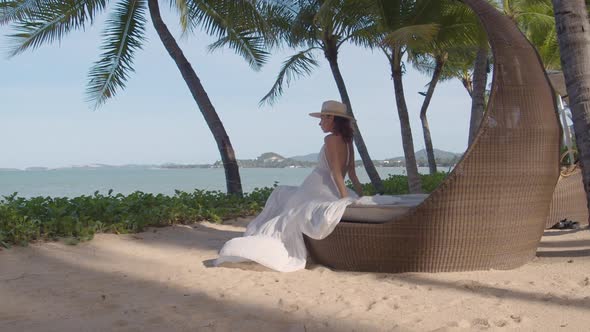 Woman Enjoying Sunset on the Beach She Dressed in White Summer Dress and a Hat alt