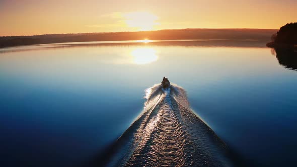 Motor boat floating on the river at sunset.  alt