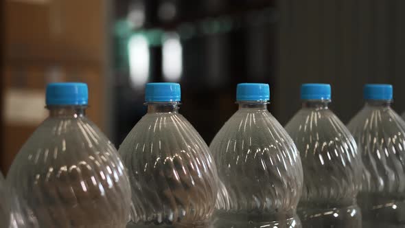 Plastic Bottles with Water Ride One After Another in a Row on a Conveyor Belt