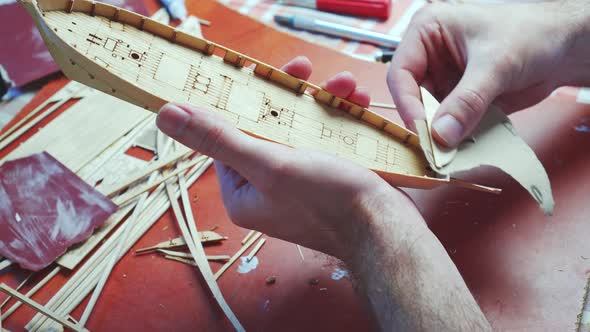 Hands of Man Adjusts Plywood Details for Ship Model Grinding on Sandpaper