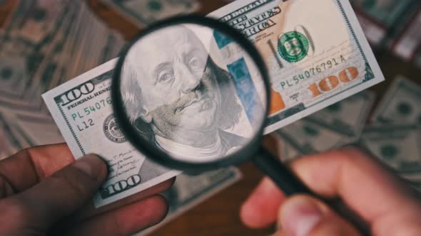 One Hundred Dollars Inspecting Under Magnifying Glass on Money Background alt