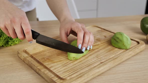 Female Hands Cut Avocado in Pieces alt
