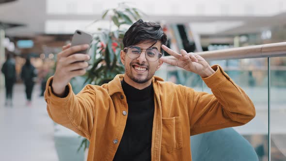 Young Handsome Arab Guy Blogger Model Holding Phone in Hand Photographed on Mobile Camera Posing alt