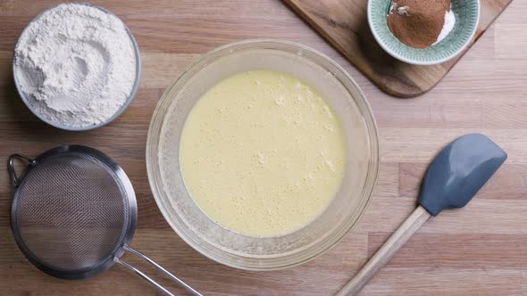Preparing Sieve For Sifting Flour In A Bowl With Liquid Ingredients Mixed. overhead shot alt