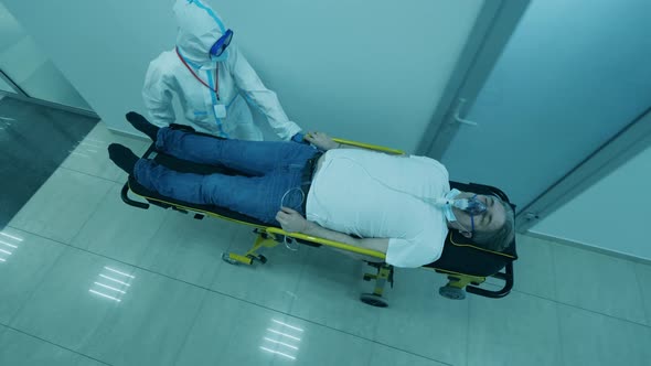 COVID-19 Patient in Coronavirus Hospital. Top View of a Male Patient Getting Relocated on a Rolling alt