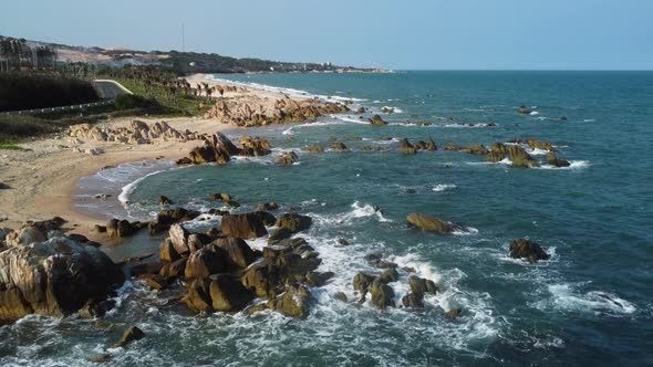 A breathtaking aerial shot of a coastline in Vietnam. Waves hit the rocks, that are rising above the alt