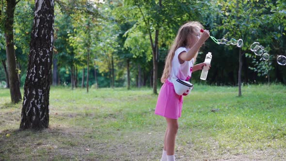 Side view of girl with bubble blower outdoors. alt