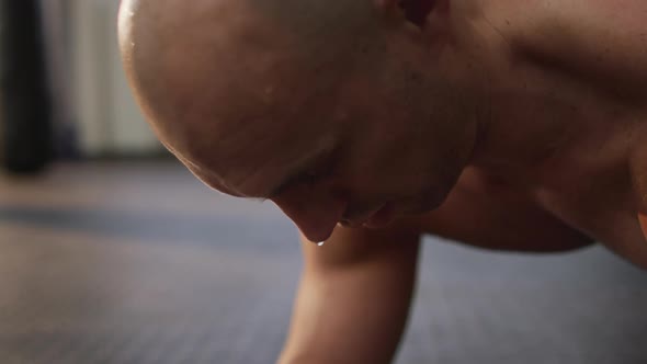 Caucasian muscular shirtless bald man exercising and doing plank alt