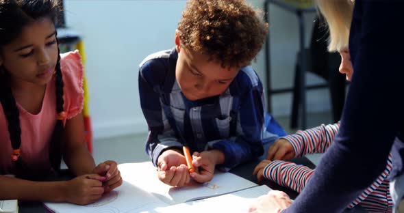 Teacher helping schoolkids with their homework in classroom alt