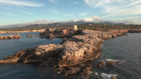 Aerial view of pirate lookout tower in Ibiza during sunset. Showing ocean, cliffs and mountains in t alt