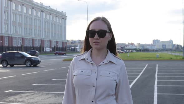 Beautiful Young Girl with Glasses Walks Through the City and Looks Around