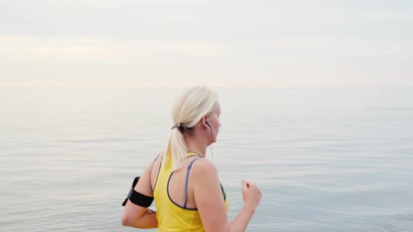 Young Woman Jogging on the Background of the Sea or Lake alt