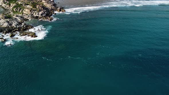 Aerial trucking shot showing rocky coastline and beach of Hy sea with beautiful blue colored water i alt