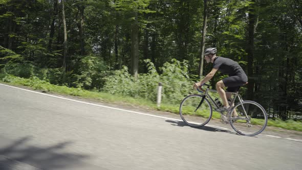 Video Man on Racing Bike Cycling on Road Through Forest