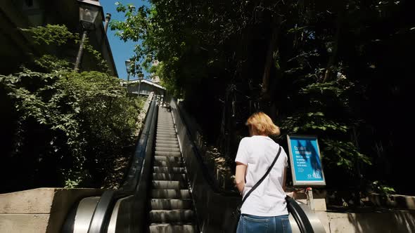 View Young Tourist Woman Looks Back Riding Modern Escalator at a Metro Station Slow Motion alt