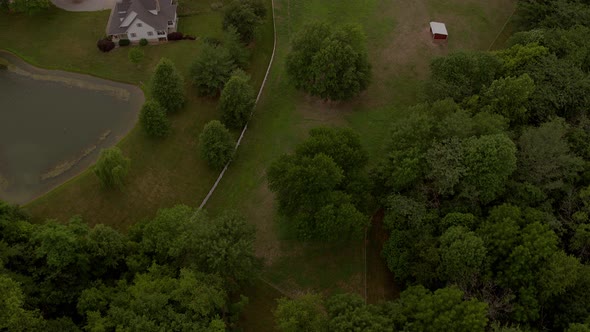 Aerial flyover a horse ranch and farm with a tilt up to reveal the horizon and farmland beyond. alt