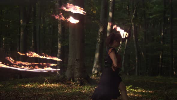 Female artist with fire staff walking in the woods, Ultra Slow Motion alt