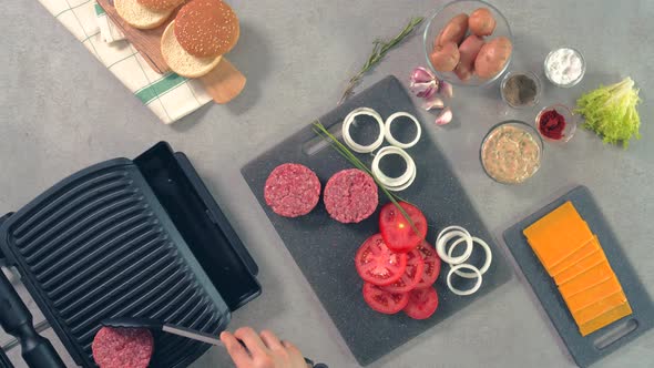 An aerial view of raw burger meat which is being placed on grilling machine by the chef alt