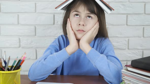 Tired child with a book on head. alt
