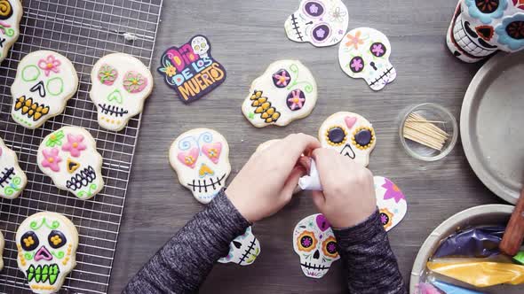 Step by step. Flat lay. Decorating sugar skull cookies with different color royal icing. alt