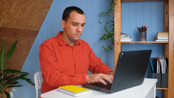 A Young Man with Working From Home at the Notebook in Cozy Room