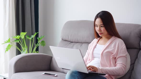 Young woman sitting at living room and working on laptop at home