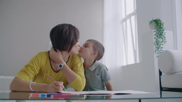 Beautiful Young Mother in a Warm Sweater Lying on the Floor with My Son Drawing with Markers on alt