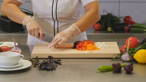 Woman Mincing Garlic on Cutting Board with Vegetables