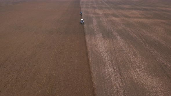 Agricultural Work in the Field, Two Blue Tractors Plow the Land