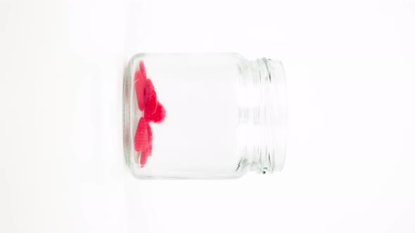 Stop motion animation small red heart into a clear glass jar, Vertical video format