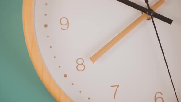Bright orange ticking clock in green background -Close up
