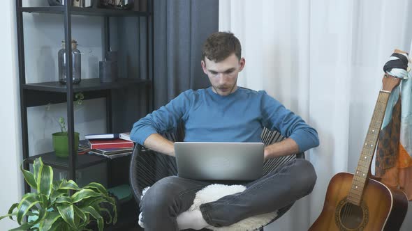 Young male freelancer finish to work on laptop computer at home office.  alt