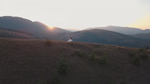 Newlyweds Running on a High Slope of the Mountain. Groom and Bride. Aerial View alt