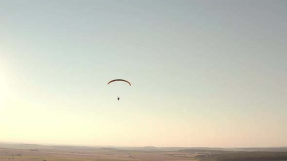 Aerial Drone View Shot of Mechanical Hang Glider Flying in Blue Sky alt