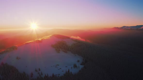 Aerial view of Winter mountain During sunrise or sunset. Pink, magenta, purple colored Sky alt